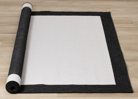 Bristol Reversible Indoor / Outdoor Rug - Cream with Black Border roll on floor