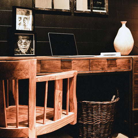 Solid acacia wood desk in honey brown finish and metal frame in an office setting.