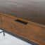 Solid acacia wood desk in honey brown finish with industrial black metal frame. Detail of desk drawer.