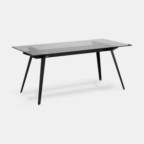 Dining table with glass top and black metal tapered legs.