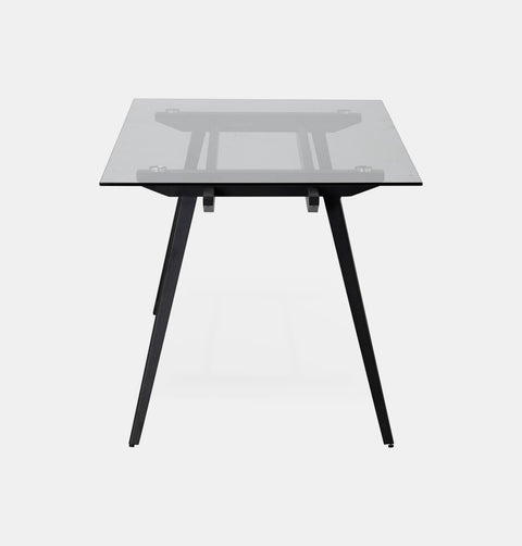 Dining table with glass top and black metal tapered legs.