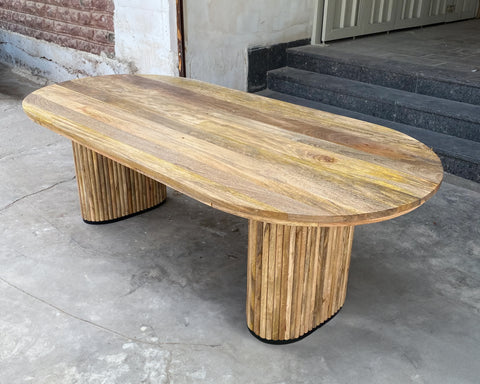 Solid mango wood oblong dining table with 2 repeating pattern ribbed legs in natural finish.
