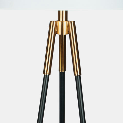 Industrial modern tripod floor lamp. White linen shade, black legs and gold accents. Detail of gold accent