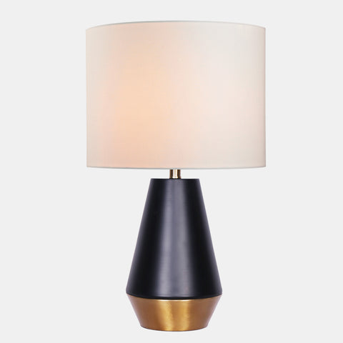 geometric modern table lamp with black and gold metal base featuring a white linen drum shade.