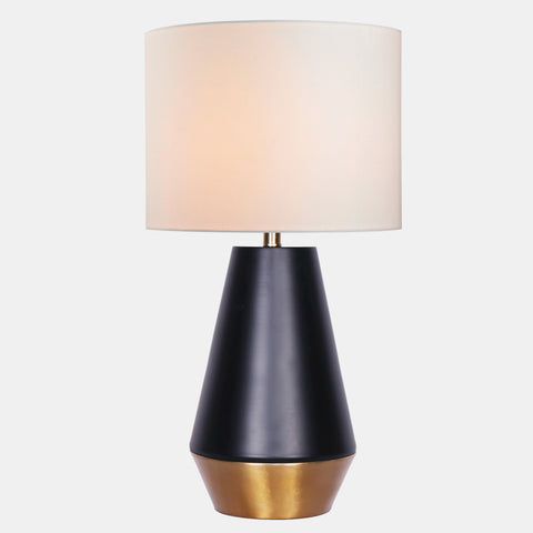 Table lamp with matte black and gold metal base, and white linen drum shade.
