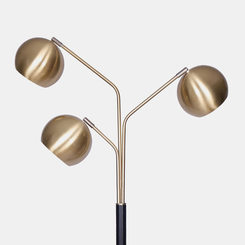 mid-century modern floor lamp with matte black metal base and 3 extended arms featuring metal orb shades in brushed gold. detail of arms with orbs.