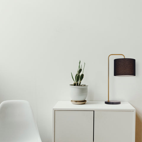 retro inspired lamp in brown on a sideboard next to a plant and chair.