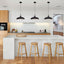 Series of Matte black metal pendant lamps with a black cord and black canopy over a kitchen island