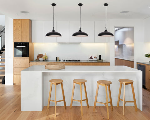 Series of Matte black metal pendant lamps with a black cord and black canopy over a kitchen island