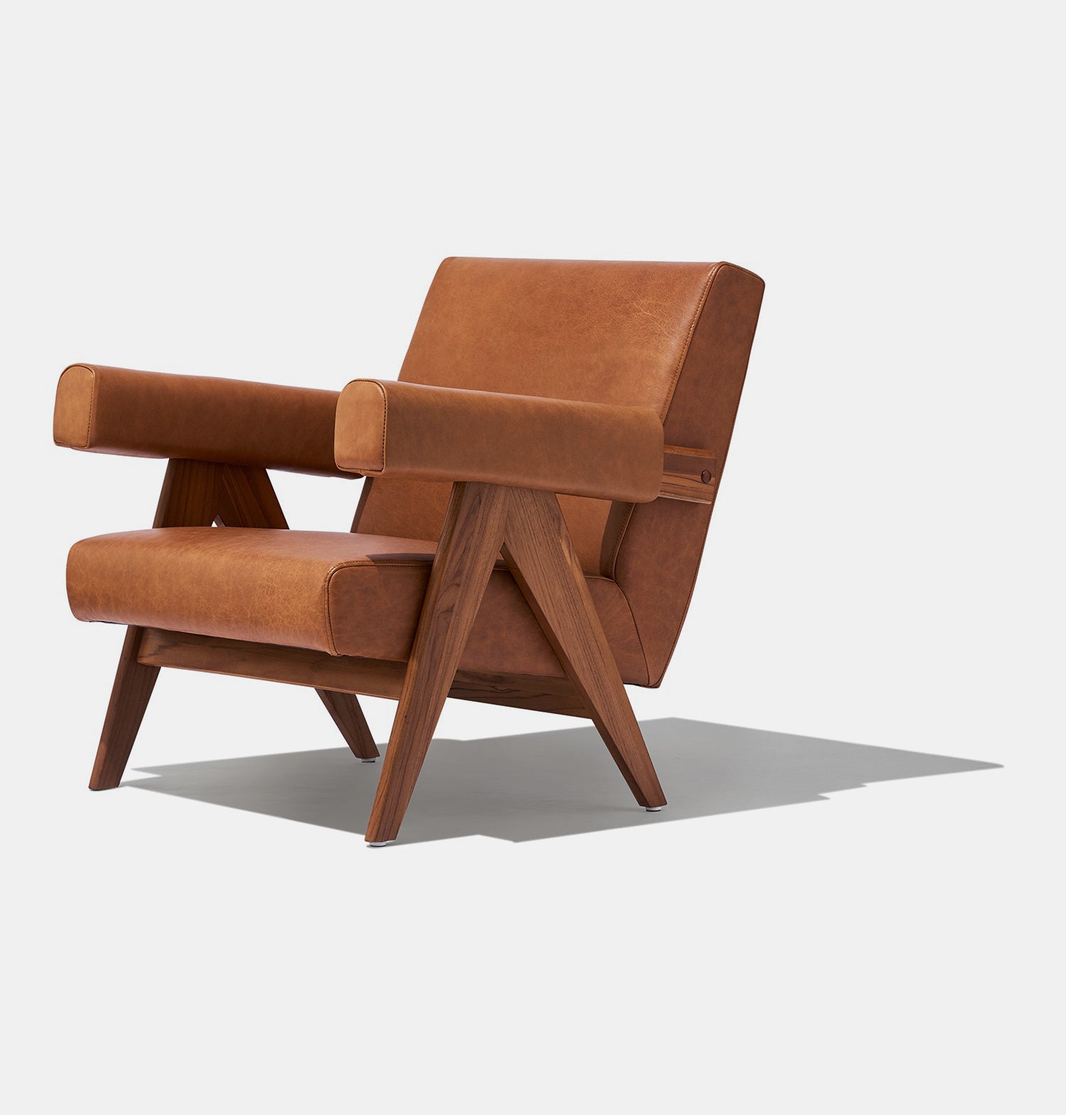 Caramel brown leather lounge chair with leather armrests and solid ash wood legs stained walnut.