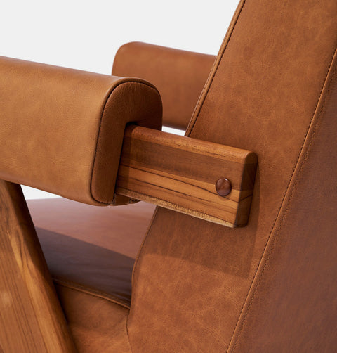 Caramel brown leather lounge chair with leather armrests and solid ash wood legs stained walnut. Armrest detail.