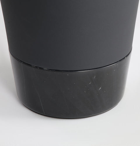 Minimal black powder coated aluminum side table resembling a pier bollard with a black marble base. Bottom detail.