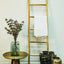 Decorative rustic ladder in natural eucalyptus wood. Towel hanging on one rung, side table with vase on left, & 3 decorative vases on floor on right.