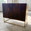Dark brown mango wood sideboard with a CNC carved repeating pyramid pattern on the two doors. Brass finished iron legs & frame.