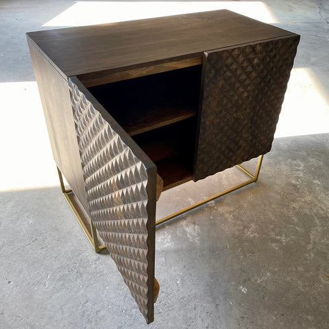 Dark brown mango wood sideboard with a CNC carved repeating pyramid pattern on the two doors. Brass finished iron legs & frame. One door open.