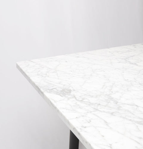 Dining table with Carrara marble top and black metal legs, marble detail.