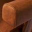 Caramel brown leather lounge chair with leather armrests and solid ash wood legs stained walnut. Front armrest detail.