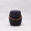 Portable dark grey cashmere pouf / stool with a brown synthetic leather strap handle.