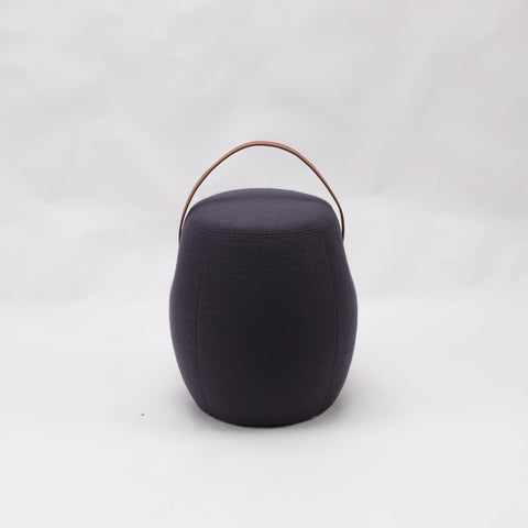 Portable dark grey cashmere pouf / stool with a brown synthetic leather strap handle.