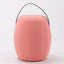 Portable pink cashmere pouf / stool with a brown synthetic leather strap handle.