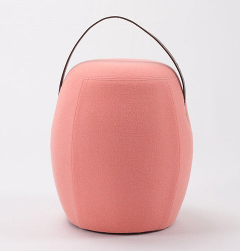 Portable pink cashmere pouf / stool with a brown synthetic leather strap handle.